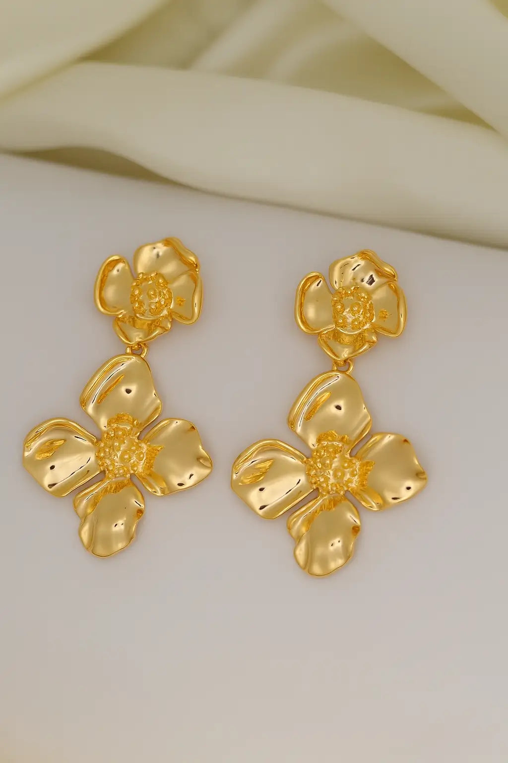 Pair of gold floral earrings on a white surface