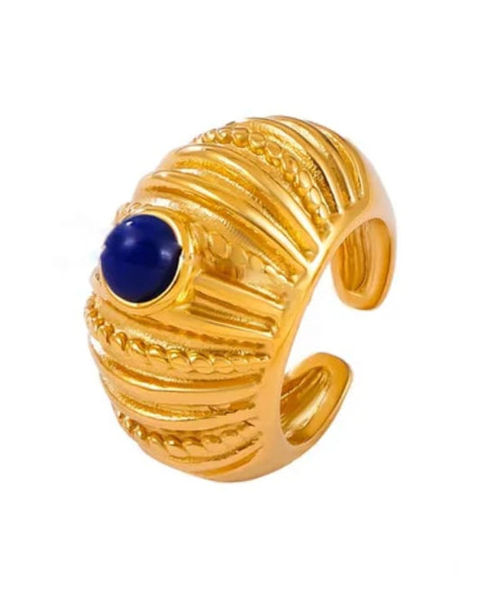 Gold ring with a blue gemstone on a white background