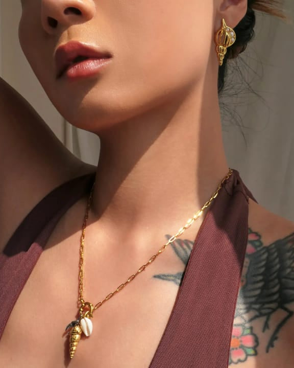 Close-up of a woman wearing gold jewelry with a neutral background