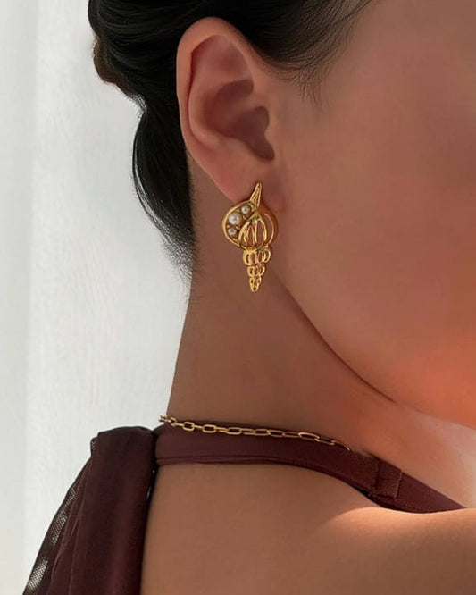 Gold earring worn by a person with a neutral background