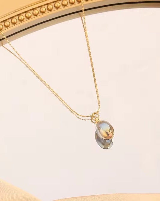 Gold necklace with a pendant on a light background