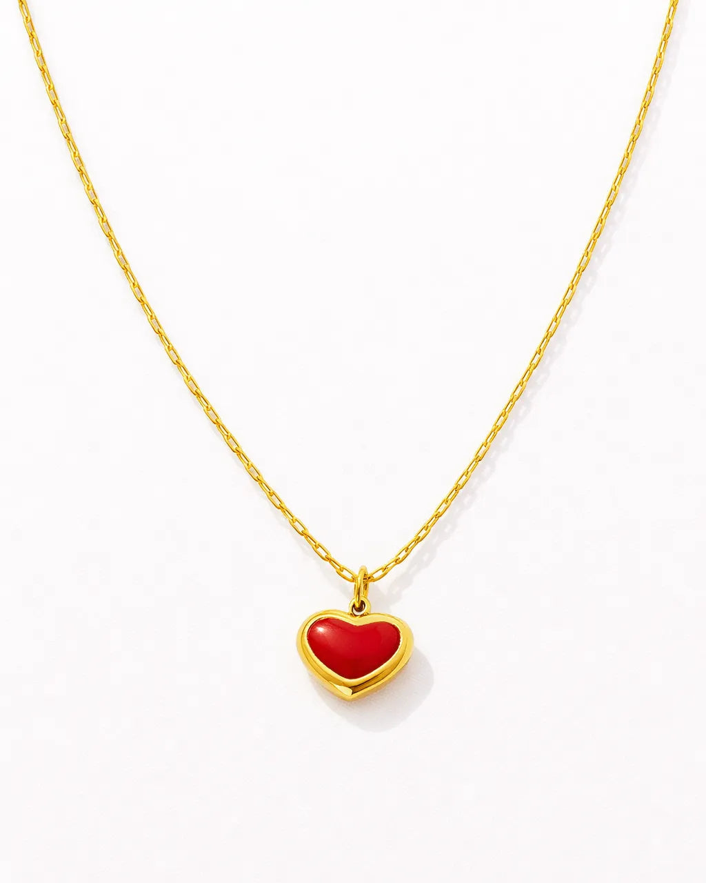 Gold necklace with a red heart pendant on a white background