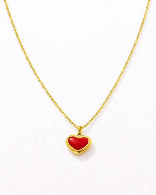 Gold necklace with a red heart pendant on a white background