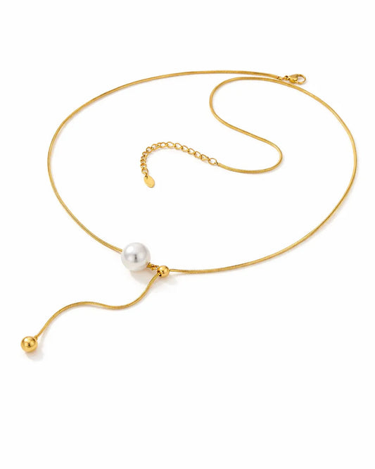 Gold necklace with a single pearl on a white background