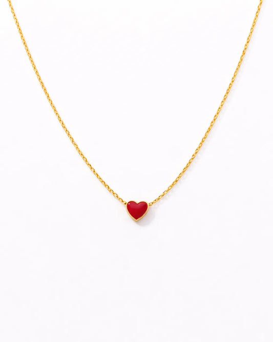 Gold necklace with a red heart pendant on a white background