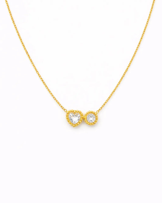Gold necklace with a heart and infinity symbol pendant on a white background