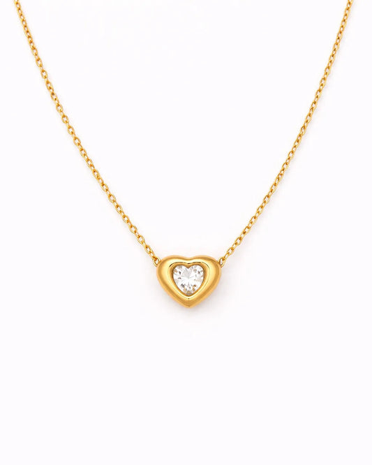 Gold heart-shaped necklace with a diamond on a white background