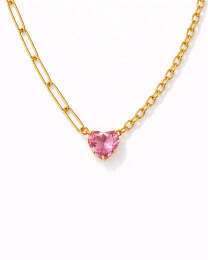 Gold necklace with a pink heart-shaped gemstone on a white background