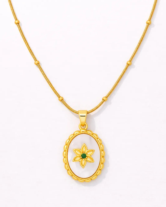 Gold necklace with a pendant featuring a green gemstone on a white background