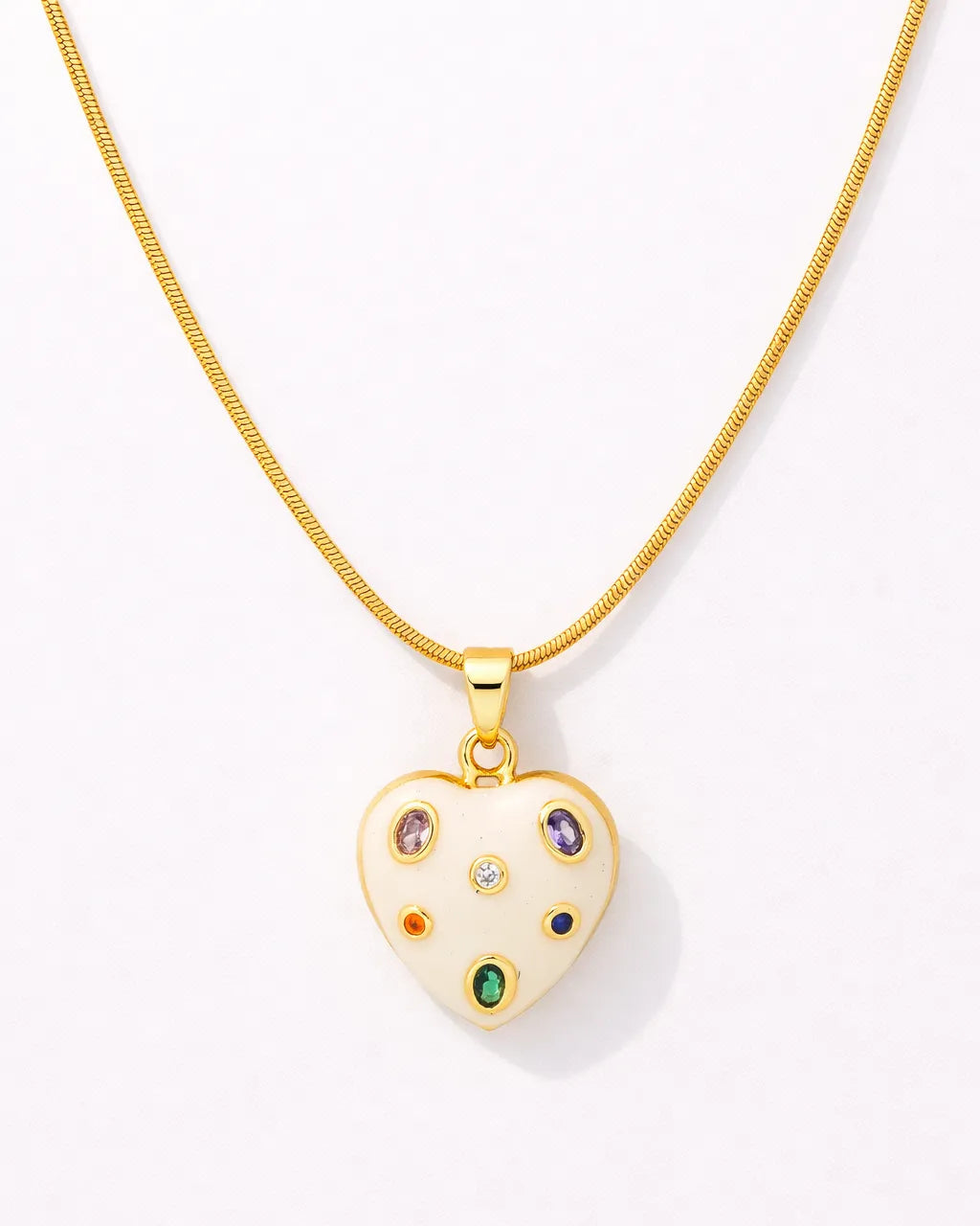 Gold necklace with a heart-shaped pendant featuring colorful gemstones on a white background