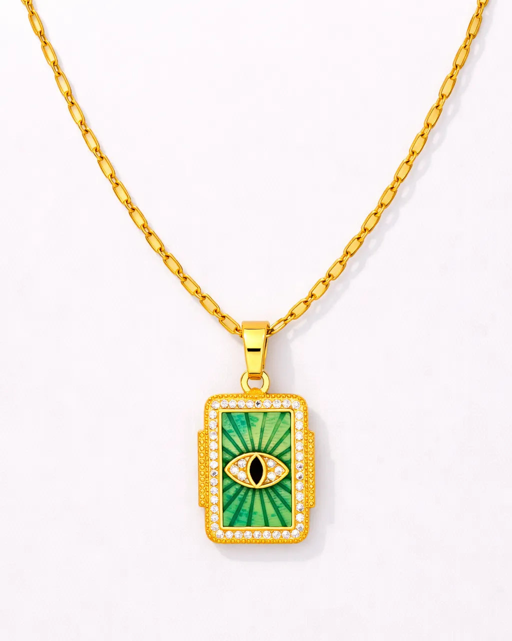 Gold necklace with a green pendant featuring an eye design on a white background