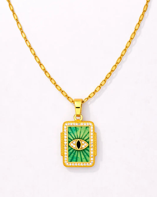 Gold necklace with a green pendant featuring an eye design on a white background
