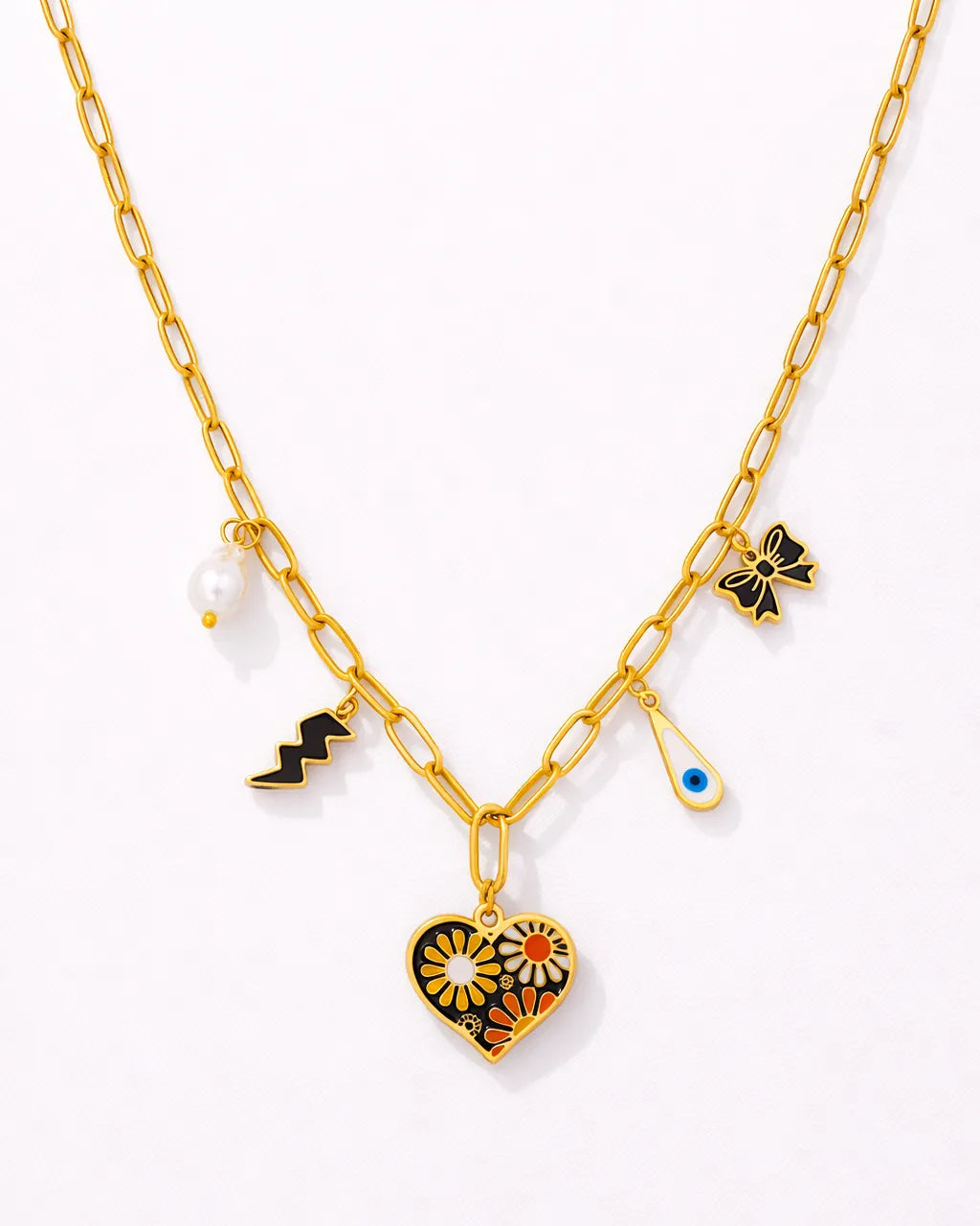 Gold necklace with heart-shaped pendant and various charms on a white background
