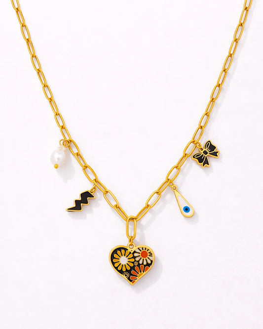 Gold necklace with heart-shaped pendant and various charms on a white background