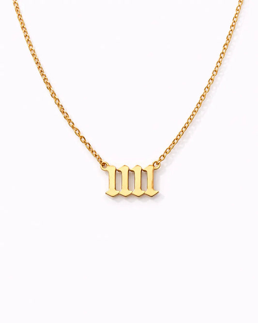 Gold necklace with a 'w' pendant on a white background