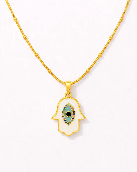Gold necklace with a hamsa hand pendant featuring an eye design on a white background