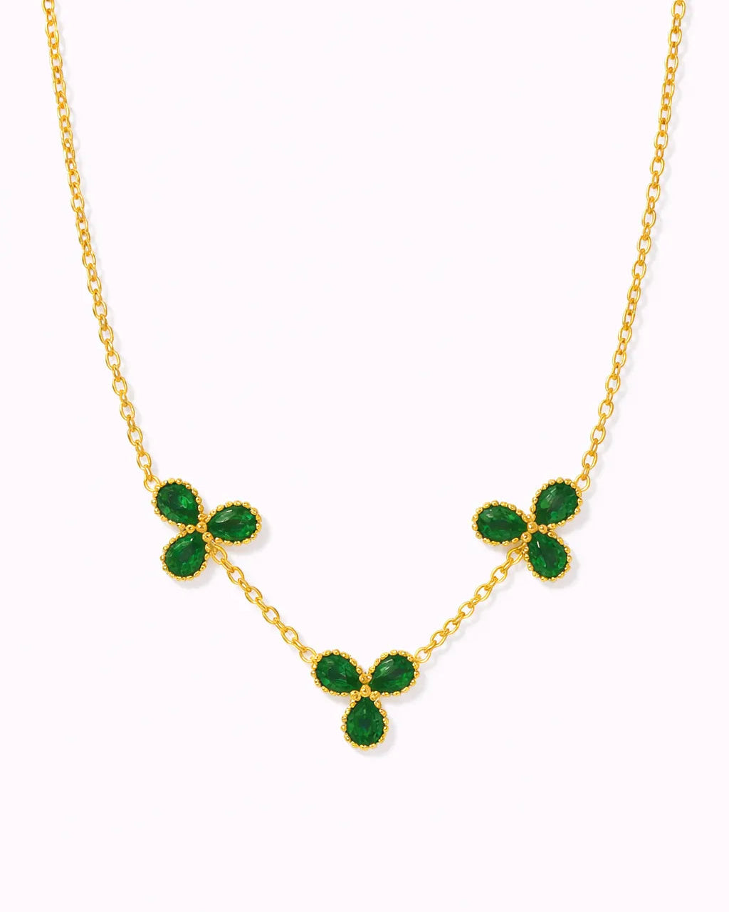 Gold necklace with green gemstones on a white background