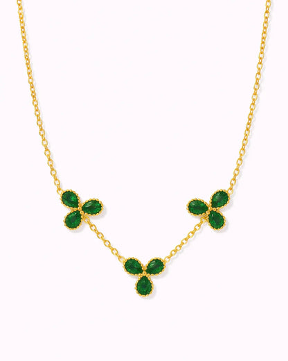 Gold necklace with green gemstones on a white background