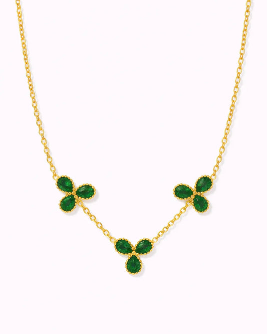 Gold necklace with green gemstones on a white background