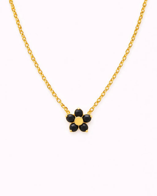 Gold necklace with a black flower pendant on a white background
