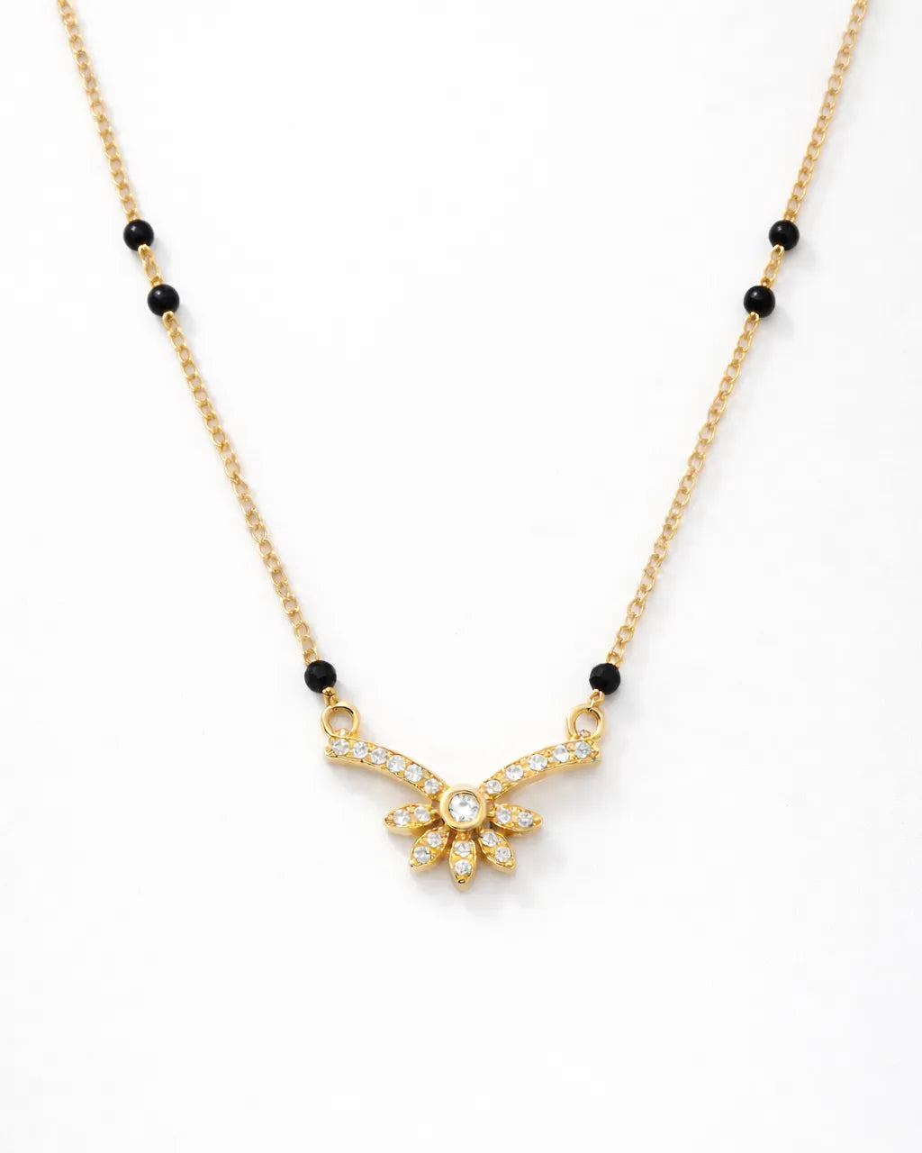 Gold necklace with black beads on a white background