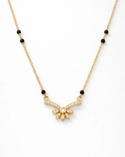 Gold necklace with black beads on a white background