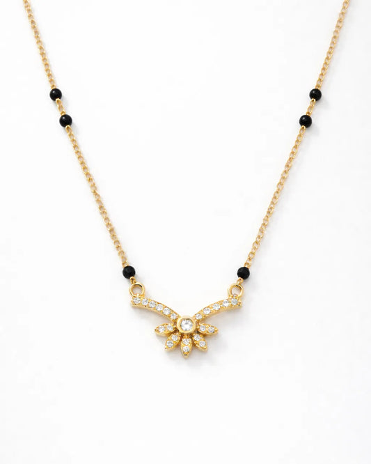 Gold necklace with black beads on a white background