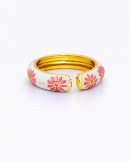 Set of three gold bangles with pink floral designs on a white background