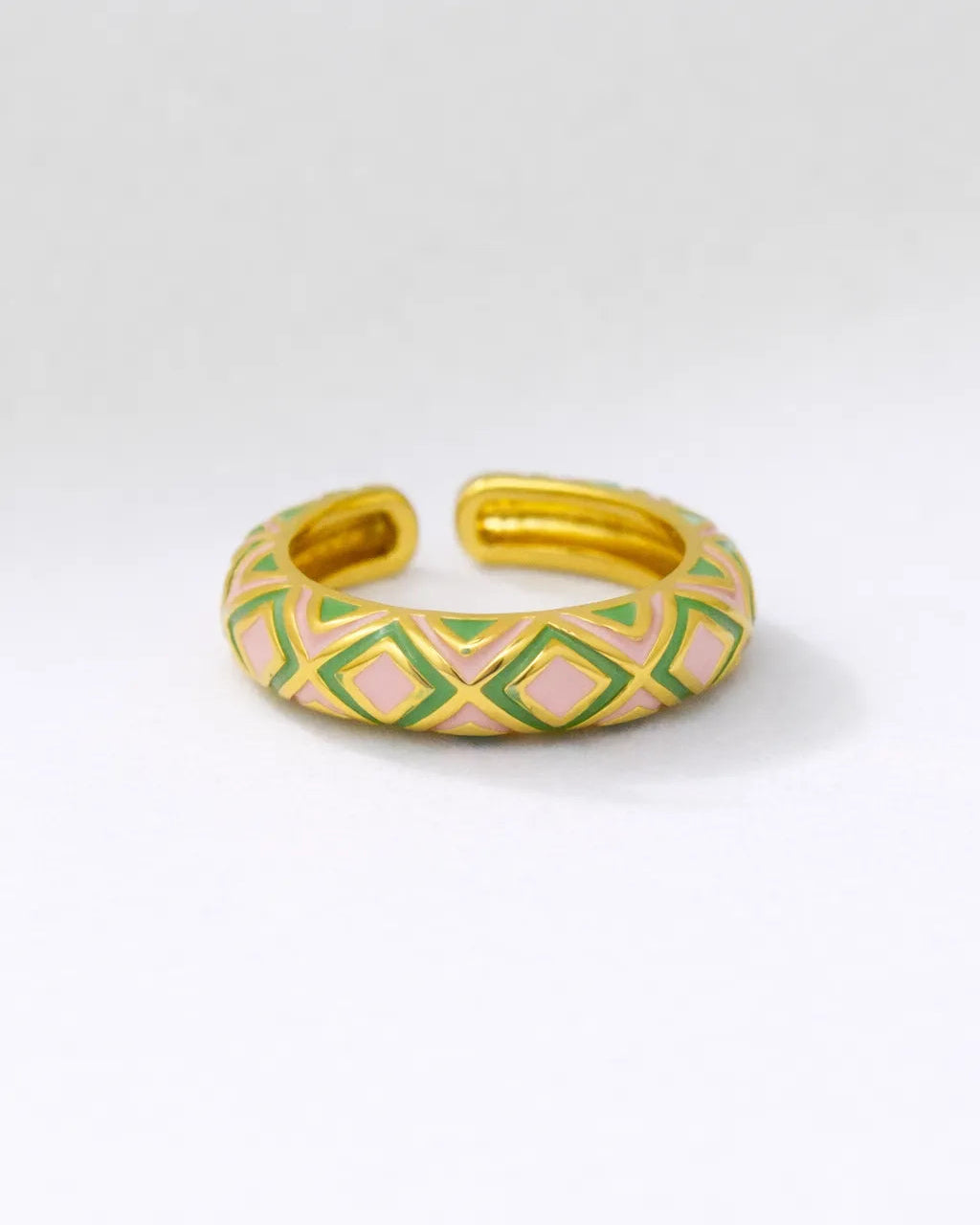 Gold bracelet with green and pink geometric pattern on a white background
