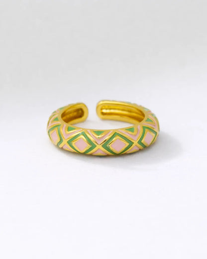 Gold bracelet with green and pink geometric pattern on a white background