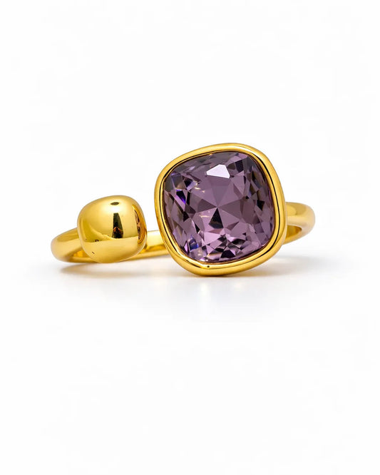 Gold ring with a purple gemstone on a white background