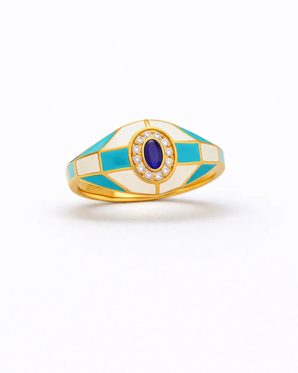 Ring with gold band, blue gemstone, and white enamel on a white background