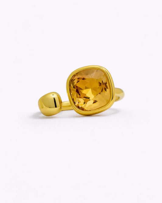 Gold ring with a yellow gemstone on a white background