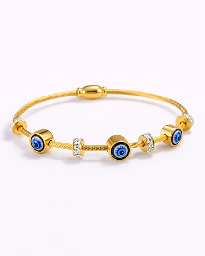 Gold bracelet with blue evil eye beads on a white background