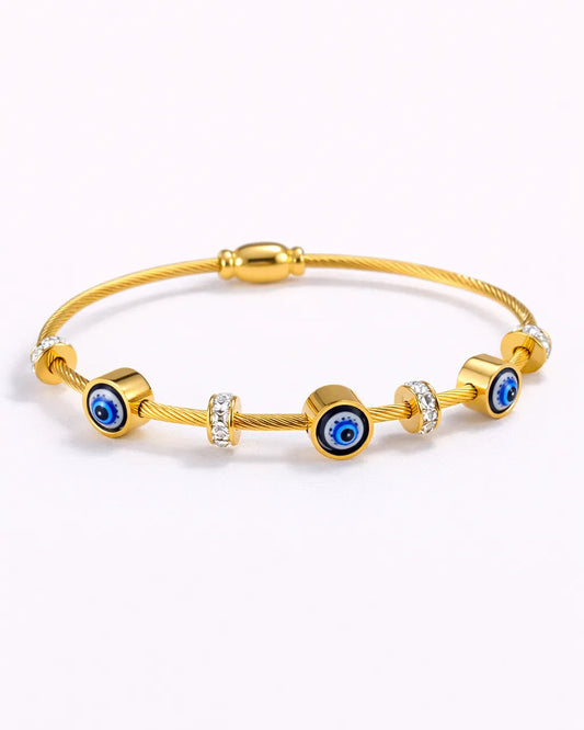 Gold bracelet with blue evil eye beads on a white background