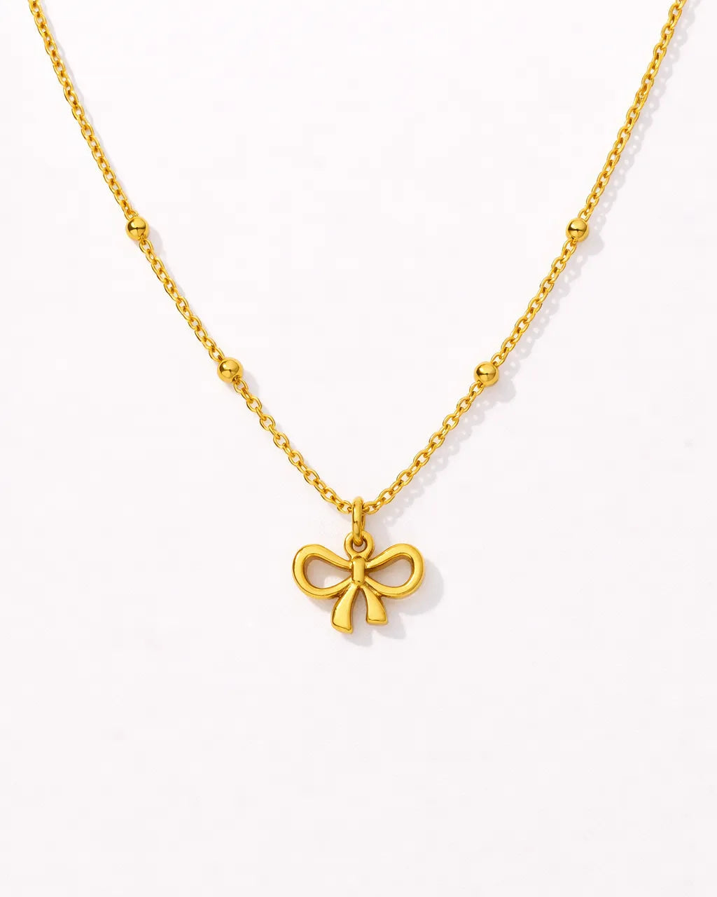 Gold necklace with a bow pendant on a white background