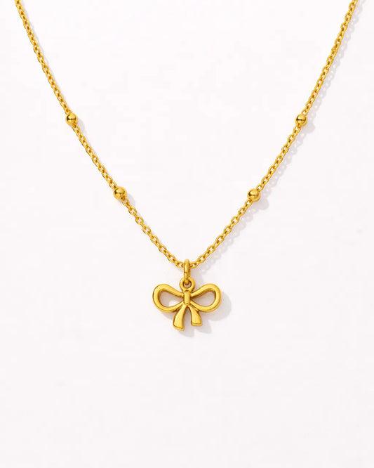 Gold necklace with a bow pendant on a white background