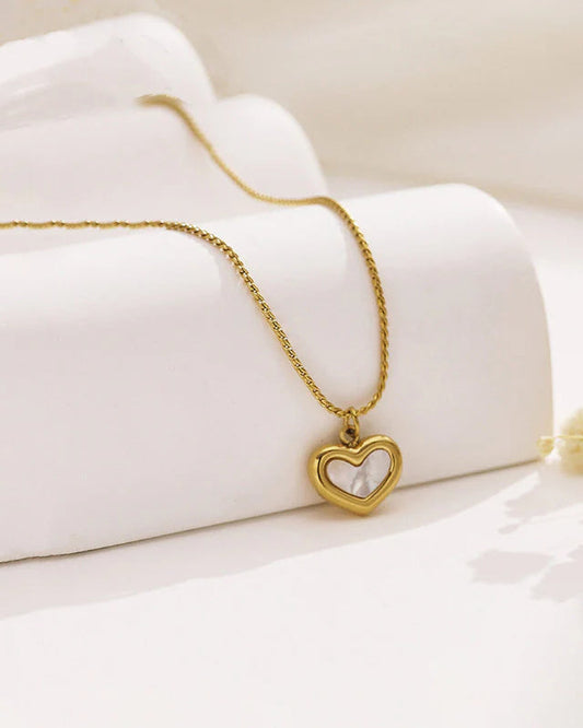 Gold necklace with a heart-shaped pendant on a white fabric background