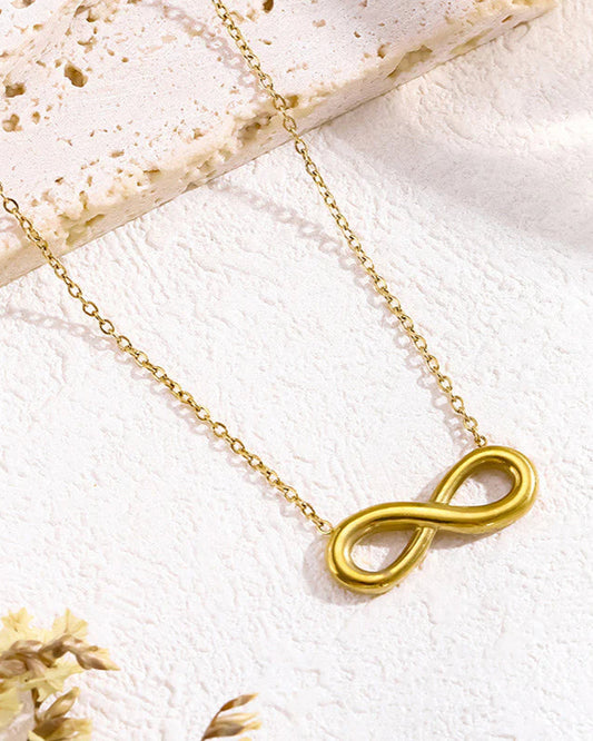 Gold infinity necklace on a light background