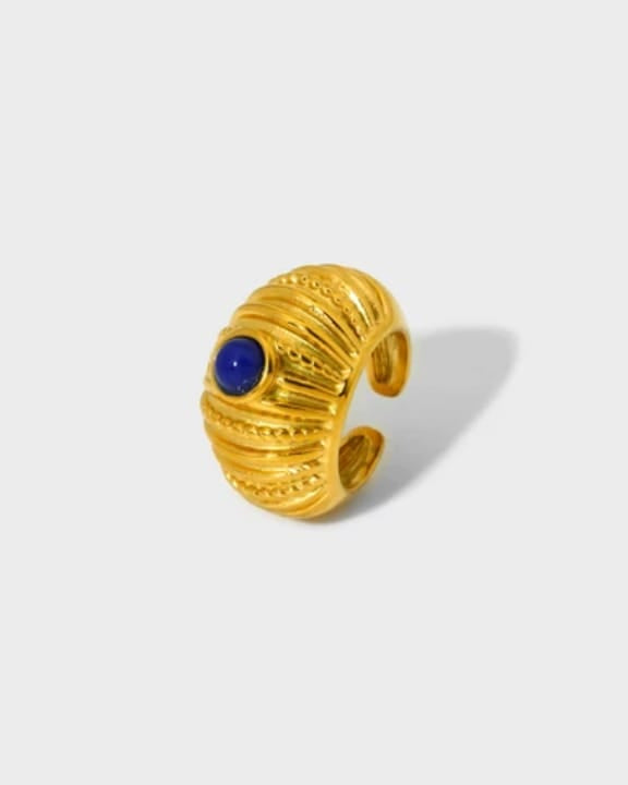 Gold ear cuff with a blue gemstone on a light gray background