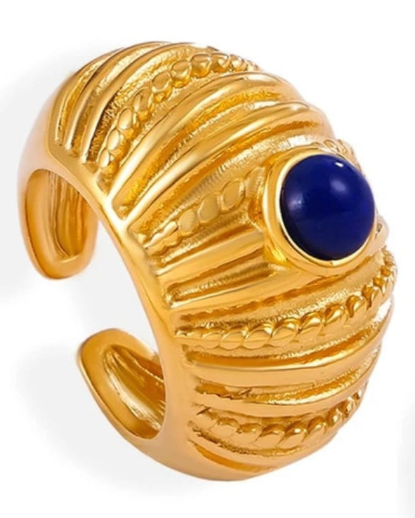 Gold ring with a blue gemstone on a white background
