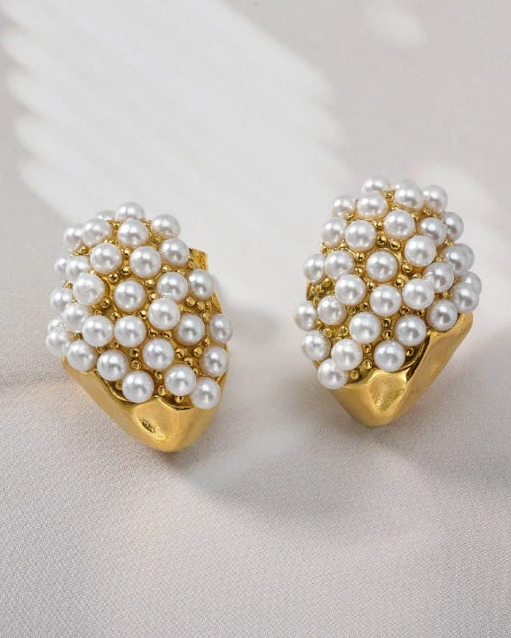 Pair of pearl earrings with gold posts on a light gray background
