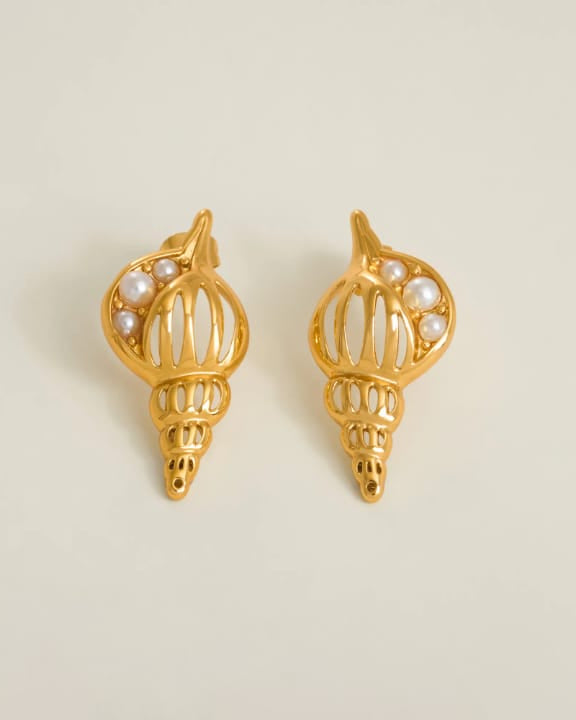 Gold shell-shaped earrings with pearl accents on a beige background
