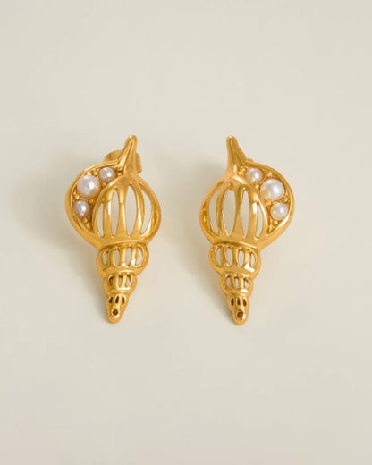 Gold shell-shaped earrings with pearl accents on a beige background