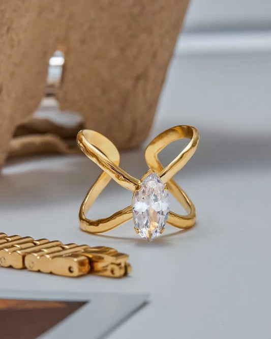 Gold ring with a clear gemstone on a neutral background