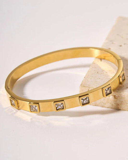 Gold bracelet with diamond accents on a light background